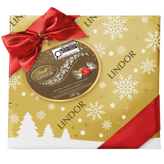 Lindt LINDOR Assorted Chocolate Truffles Gift Box, 287g, features festive white snowflake and tree designs with a red ribbon and bow, plus Lindt Lindor branding and product details.
