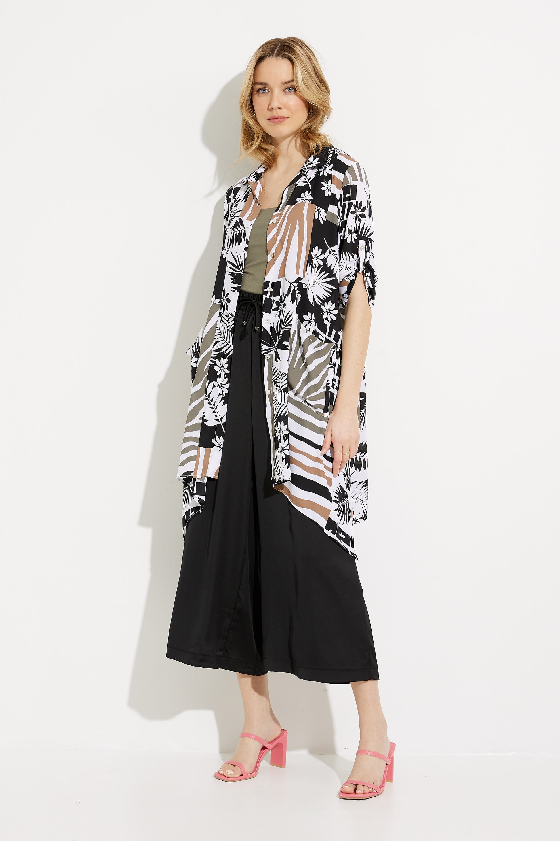 A person with long hair is wearing a black and white patterned kimono, a khaki green top, stylish Drawstring Cropped Pants Style 232113 by Joseph Ribkoff with a stretchy waist, and pink heeled sandals. They are standing against a plain white background.