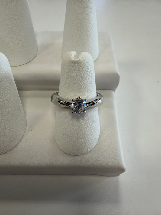 Jenna 64 Ring featuring a CZ solitaire with a round, prong-set gemstone on a polished silver stretch band, displayed on a white ring stand.