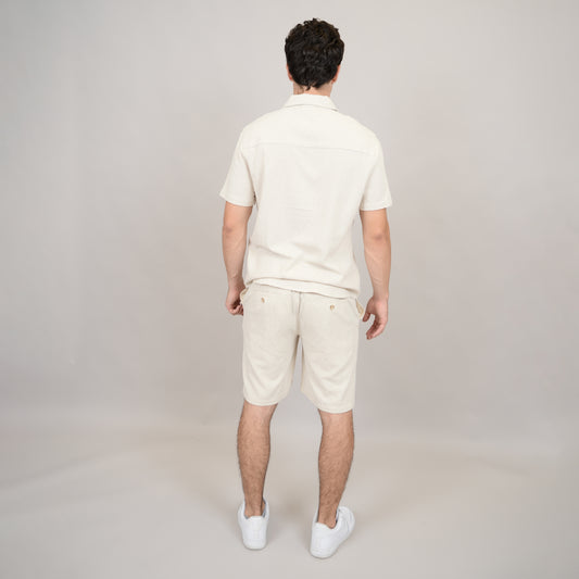 A man faces away from the camera, wearing the HEDGE Linen Blend Short Sleeve Button Shirt 56MW104S with matching shorts and white sneakers, set against a plain light background.