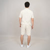 A man faces away from the camera, wearing the HEDGE Linen Blend Short Sleeve Button Shirt 56MW104S with matching shorts and white sneakers, set against a plain light background.