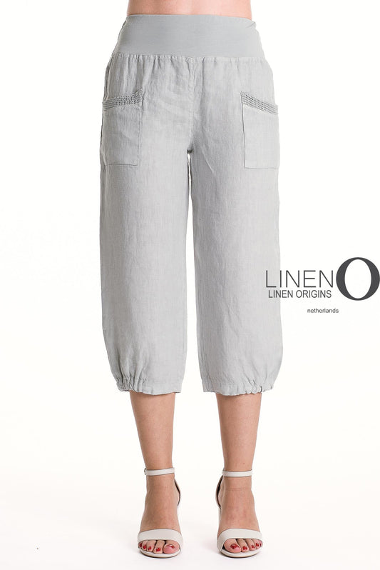 A person wears LinenO's French Linen Capri PT878-152 in Grigio Chiaro with elastic waist and cuffs, front pockets, and pairs them with light gray heeled sandals. The "Linen Origins Netherlands" logo is visible.