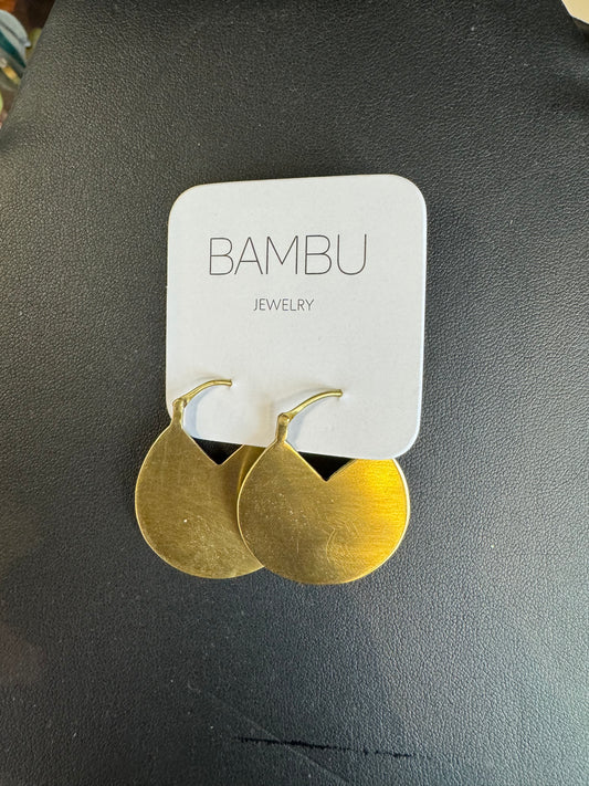 A pair of gold-colored circle earrings is attached to a white card labeled "BAMBU Jewellery." The earrings, showcasing a modern design with a smooth, slightly brushed finish, are displayed against a dark background.