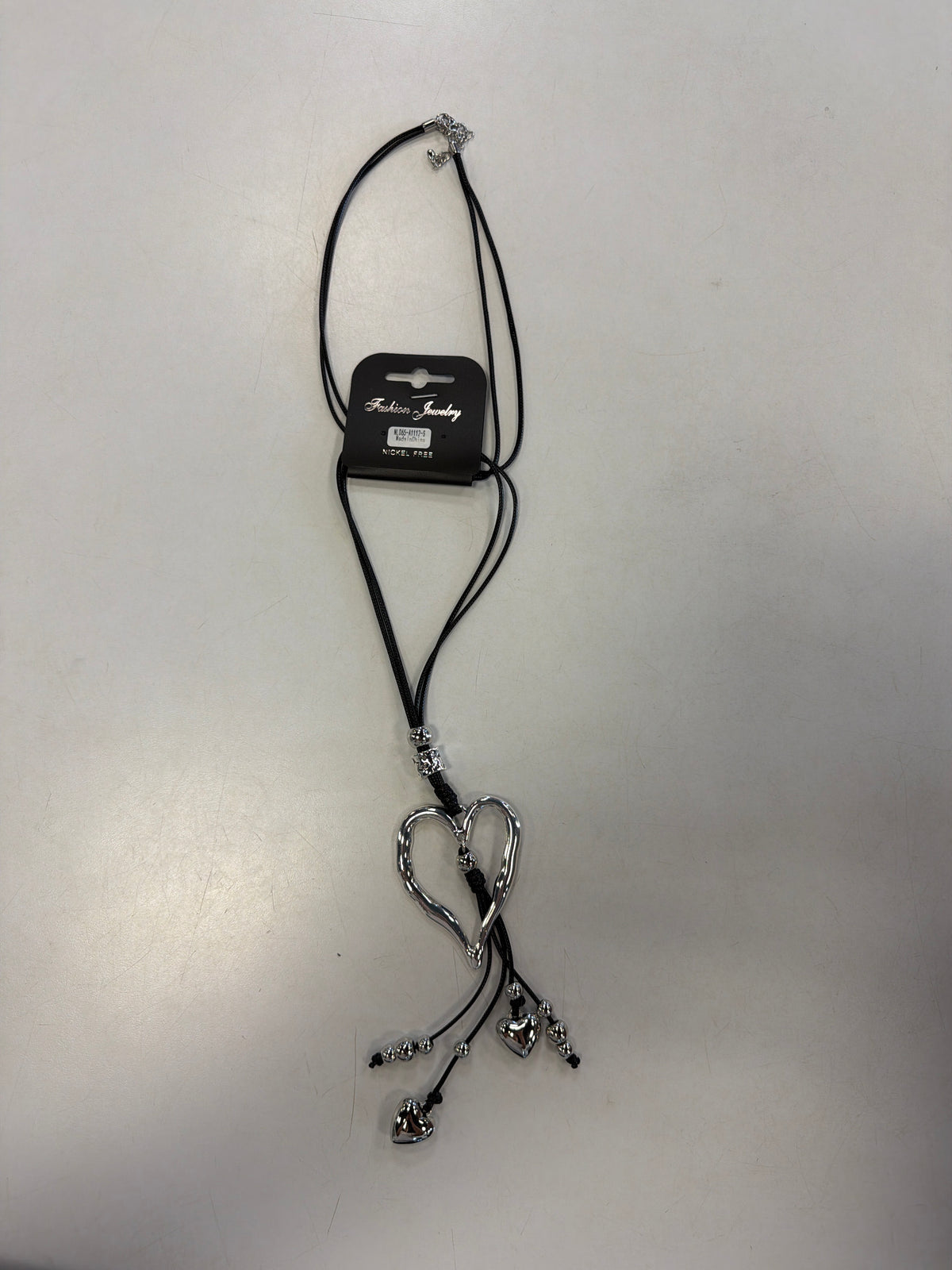 Sofia 41 necklace featuring a long black cord, a large open-heart pendant, and dangling silver-tone heart charms.