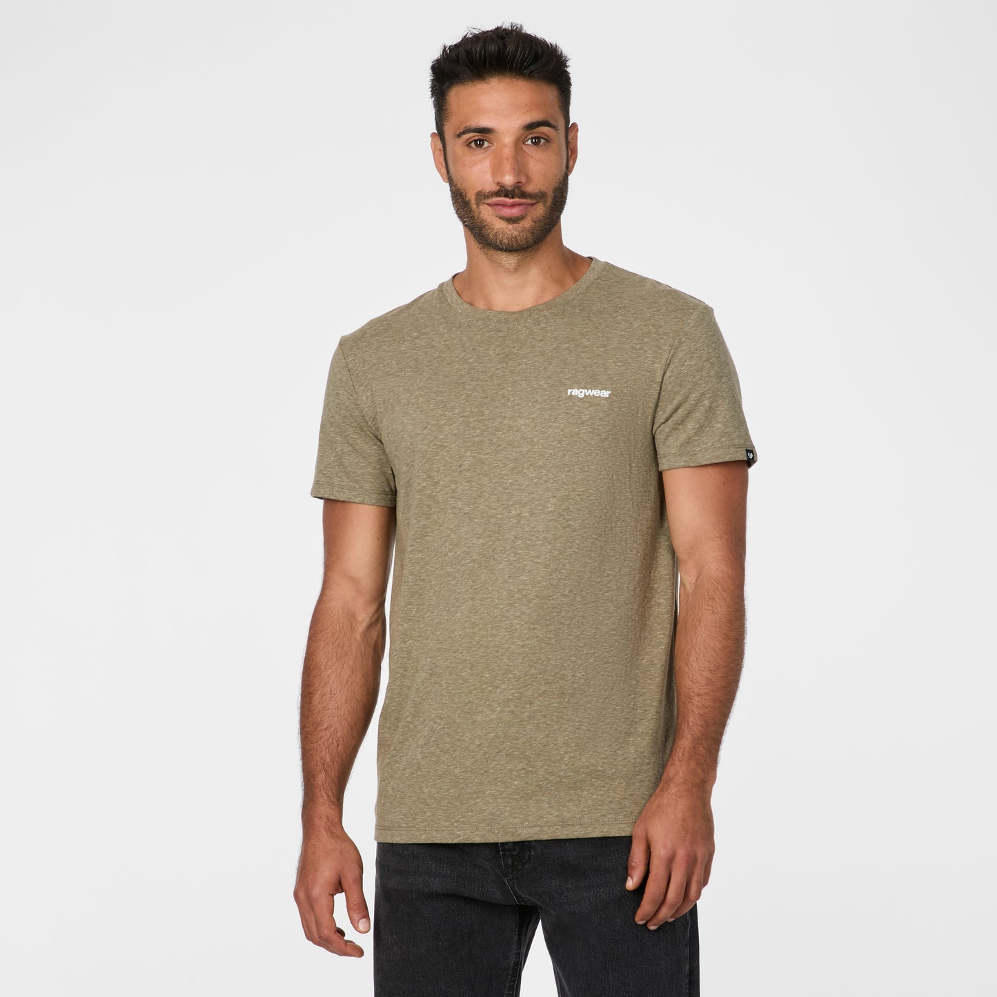 A man with short dark hair and a beard stands against a white background, facing forward in the RAGWEAR Hallys Tee 2612-15004 Dark Olive 5010, paired with black jeans, perfectly showcasing this men's casual tee.