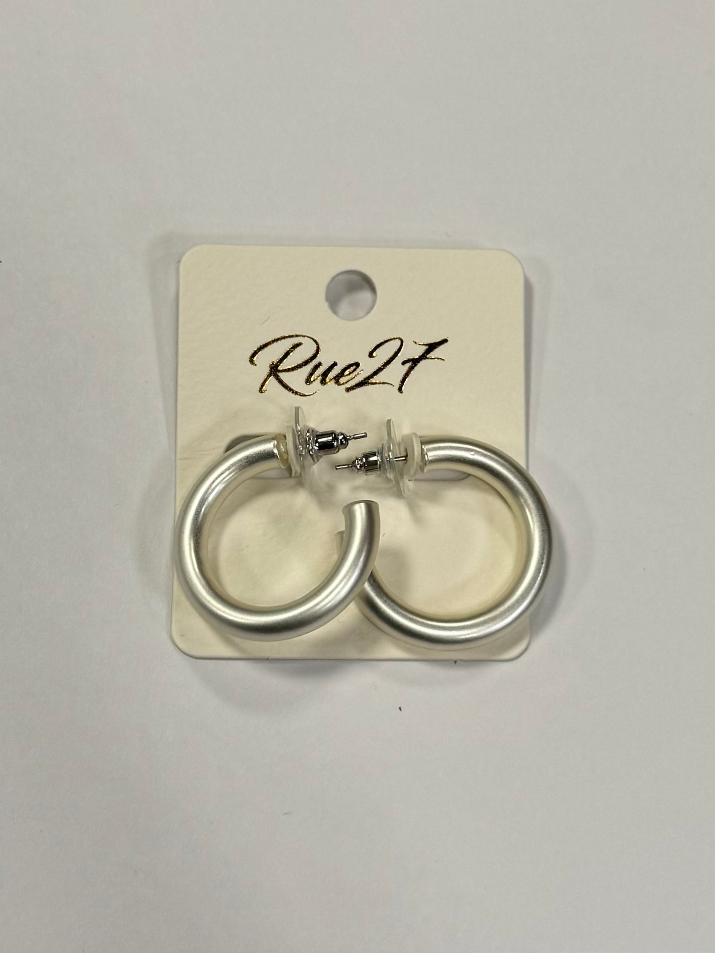 A pair of silver hoop earrings with a loop design and stud backs, identified as Dana 46 Earrings from Elise Accessories, are attached to a display card labeled "Rue2F" against a plain white background. The brand behind these stylish earrings is Posies Flowers & Fashion Inc.