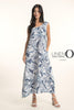 A woman with long dark hair wears white heeled sandals and the sleeveless, ankle-length French Linen Dress TP1720P-11 Bianca, featuring a blue and white leaf pattern by LinenO. "LINEN O" appears beside her against a light background.