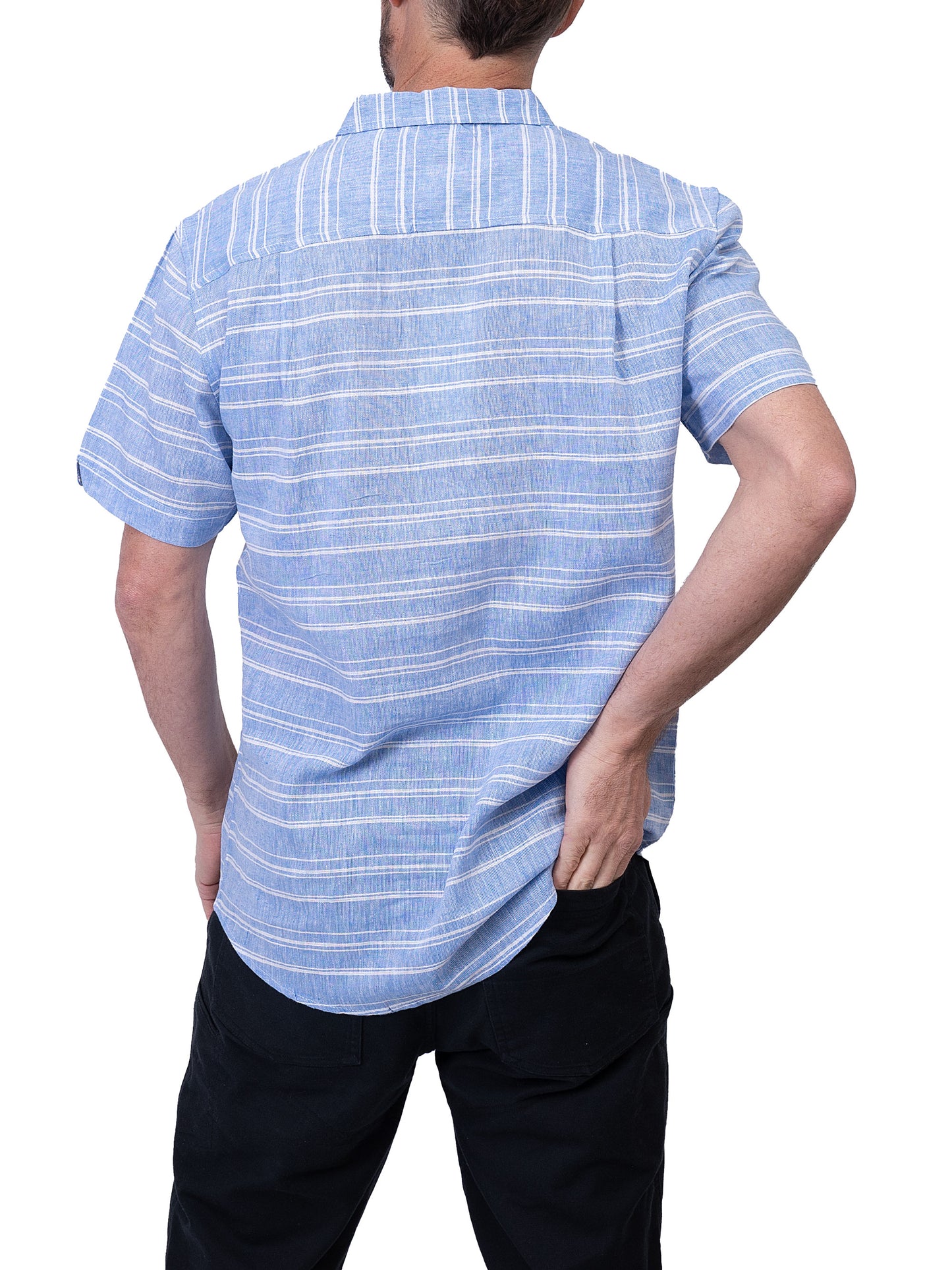 A person is wearing a Men’s Shirt Short Sleeve- BLUE STRIPE and black pants from Silver Jeans Co. The person is facing slightly left, with their right hand holding the summer shirt near the buttons and their left hand resting near their hip.