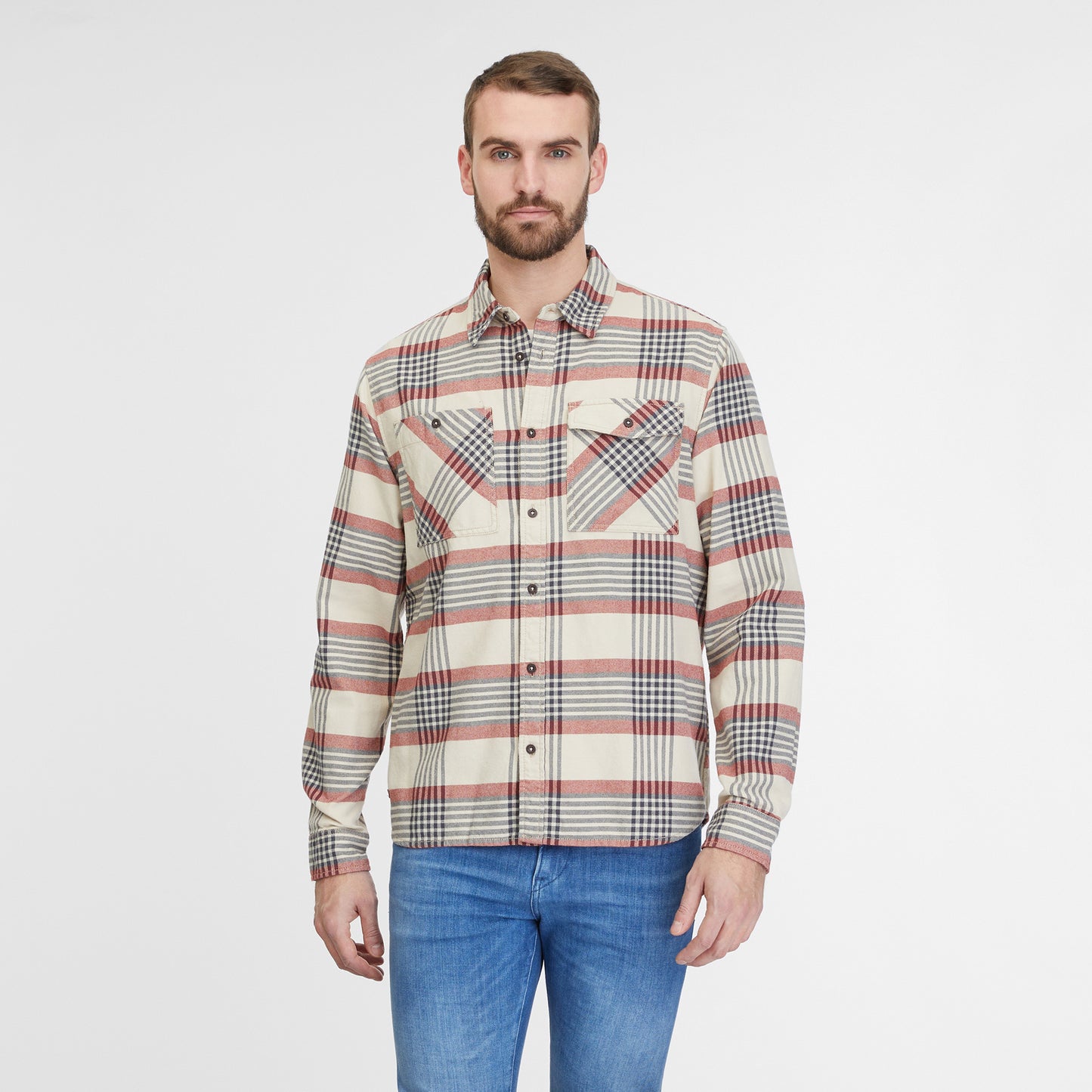 A man with short hair and a beard is standing against a plain white background. He is wearing the Shirt Checki Ecru 2422-40003-7004 by RAGWEAR, featuring a beige, red, and black plaid pattern made from vegan streetwear-inspired cotton flannel, paired with blue jeans. He is looking directly at the camera with a neutral expression.