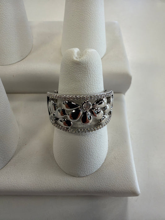 Jenna 94 Ring by Elise accessories, a wide silver stretch band ring featuring a floral design set with small stones on a display stand.