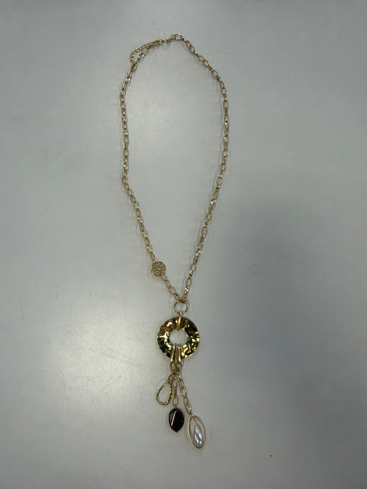 Ava 24 Necklace by Elise accessories, featuring a gold chain and a textured disc pendant with a gold bar, a dark red oval stone, and an oval pearl-like charm.