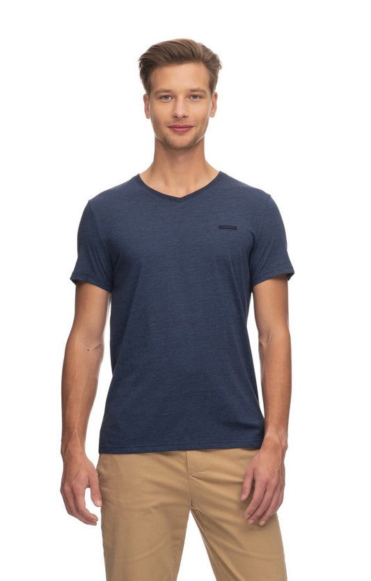 A man with short brown hair is wearing a beige pair of pants and a plain navy blue V-neck t-shirt from RAGWEAR's VENIE collection. He stands facing the camera against a plain white background, with a neutral expression and his arms relaxed by his sides.