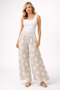 A woman smiles in a white tank top and Bella Amore Linen Pant 30201 Beige, paired with sandals and minimal jewelry, posing against a plain white background.