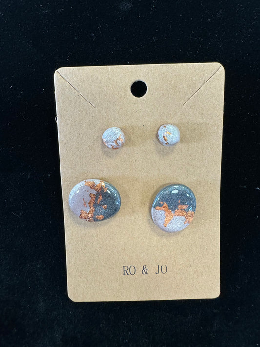 A set of four handmade polymer clay earrings from RO&JO, displayed on a cardboard tag. The Ro&Jo Earrings 445 includes two pairs: a pair of small round studs and a pair of larger round earrings, both featuring a gray background with copper-colored accents. The tag reads "RO & JO.