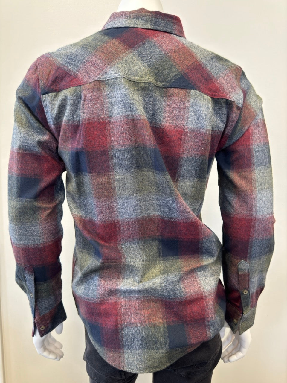 The mannequin is showcasing the Shirt Long Sleeve - BURGUNDY, a button-up flannel with a plaid pattern in shades of red, green, gray, and blue. Expertly paired with denim from Silver Jeans Co., this shirt boasts a single chest pocket and is displayed with the sleeves down and buttons fastened.