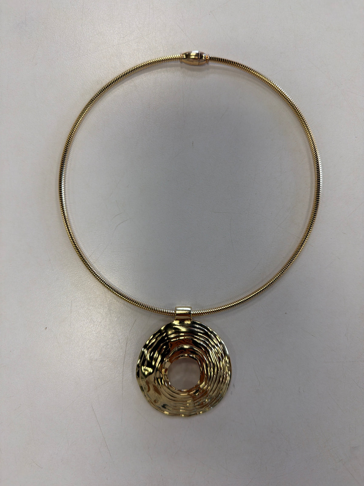 Roxanne 50 Necklace by Elise accessories, a gold choker featuring a textured circular pendant with a center cutout and a magnetic clasp.