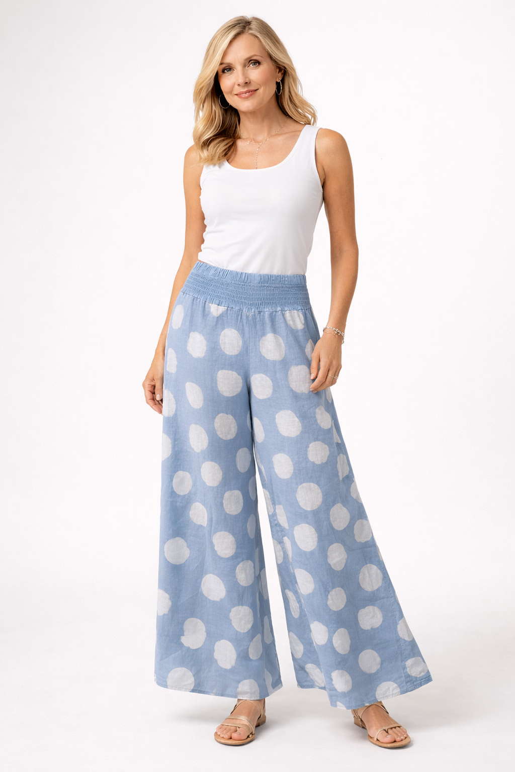 A woman in a white sleeveless top, Bella Amore Linen Pant 30201 Blue, and beige sandals stands against a plain white background.