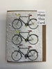 A Seeded Memories greeting card features an illustration of three bicycles in black, red, and yellow on textured white paper, with a "Plant This Card" label in the top right corner showcasing its eco-friendly design.