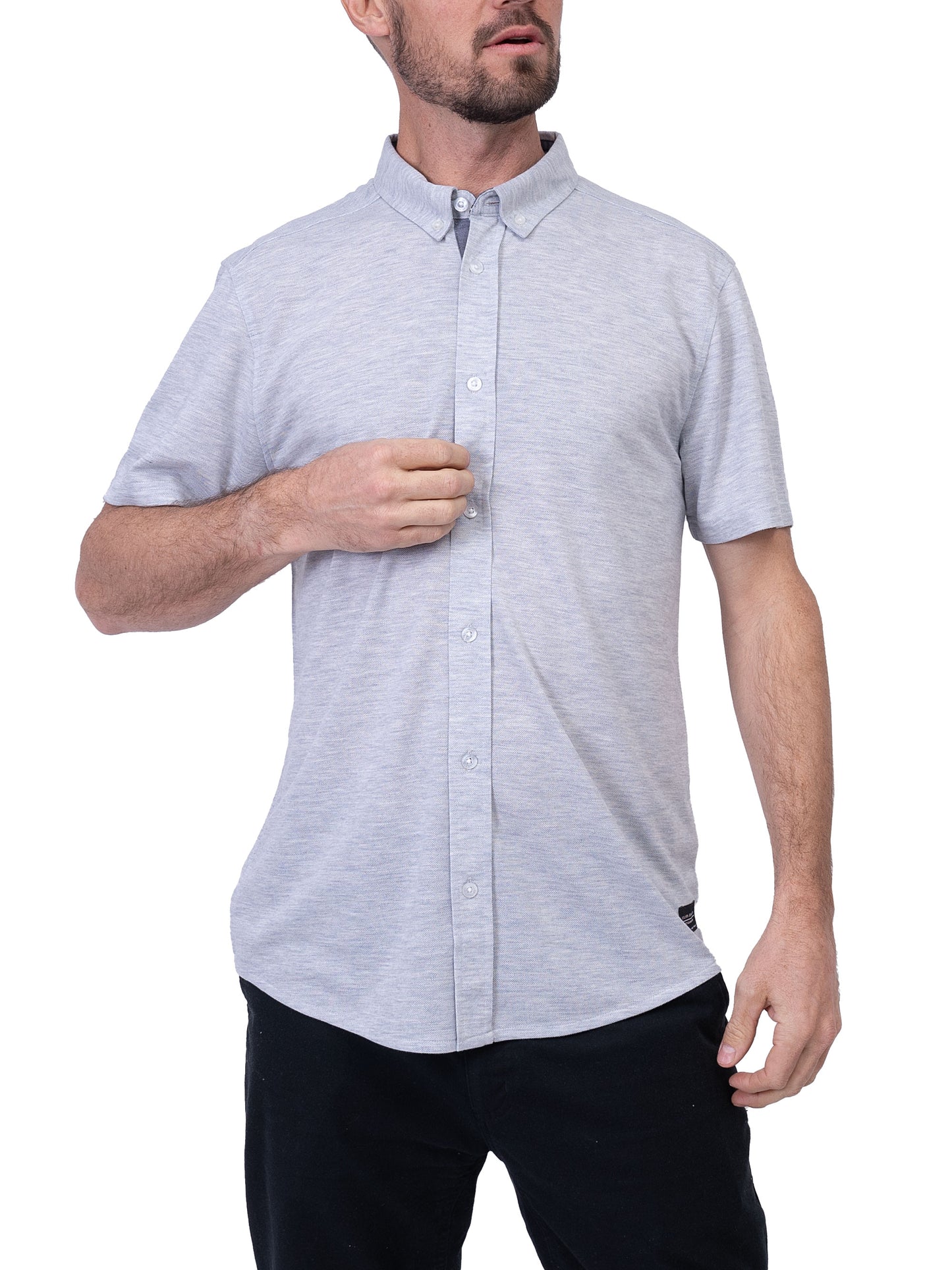 A man with a beard holds the top button of his Men’s Shirt Short Sleeve - LIGHT GREY from Silver Jeans Co. with his right hand. His left hand rests on his hip, complementing the relaxed vibe of his short-sleeved button-up shirt and dark pants.