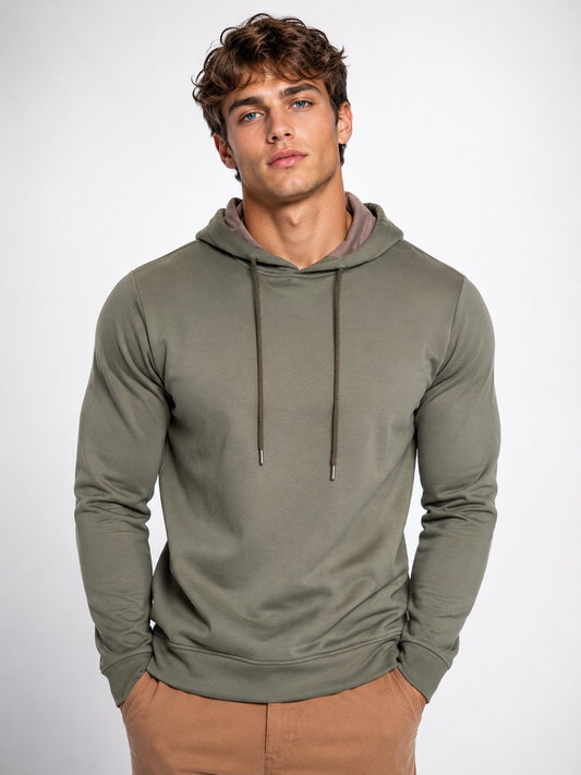 A young man with curly brown hair stands with hands in his pockets, wearing a Paul Miranda Sweatshirt Joggings FE104 and tan pants against a plain light background.