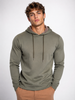 A young man with curly brown hair stands with hands in his pockets, wearing a Paul Miranda Sweatshirt Joggings FE104 and tan pants against a plain light background.