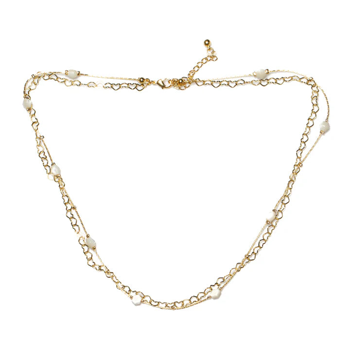 The Suzie Blue Heart Chain Necklace with White Bead in Gold Plate is a delicate, double-layered chain necklace adorned with small white pearls. This elegant and lightweight piece features an adjustable clasp for customizable length.