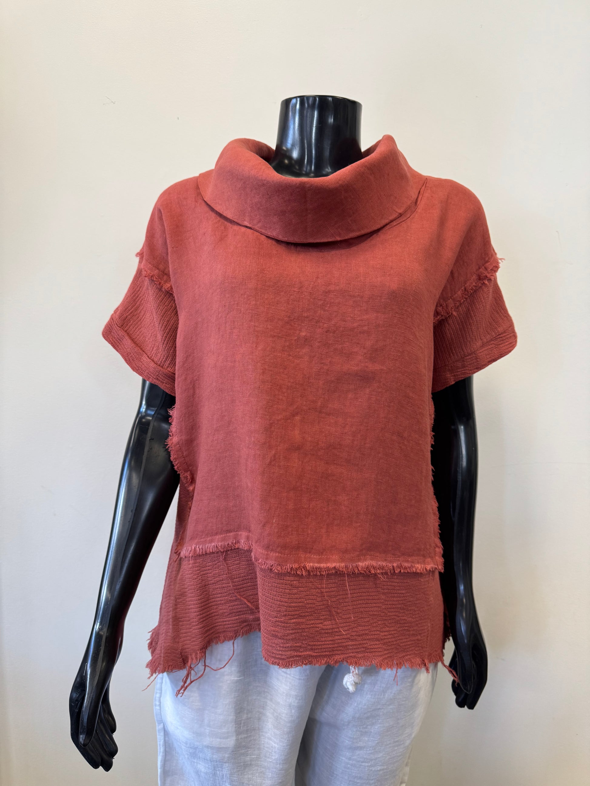 The Linen Top 3896 - Bella Amore, designed in Italy by Bella Amore, is an elegant red short-sleeved top with a wide collar. It features 100% textured linen and a frayed hem, displayed on a black mannequin, beautifully paired with white pants against a pristine white background.