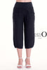 A person stands against a white background wearing LinenO's French Linen Capri PT878-74 Nero, featuring premium linen, front pockets, and an elastic waistband, paired with white high-heeled sandals.