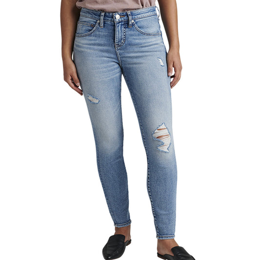 A person is wearing the Cecilia Mid Rise Skinny Jeans by JAG, which are light blue, high-waisted skinny jeans made with power stretch denim and featuring distressed details around the knees and thighs. These jeans have a button and zip closure, belt loops, and pockets. The person is also wearing black, closed-toe shoes and a tucked-in shirt.