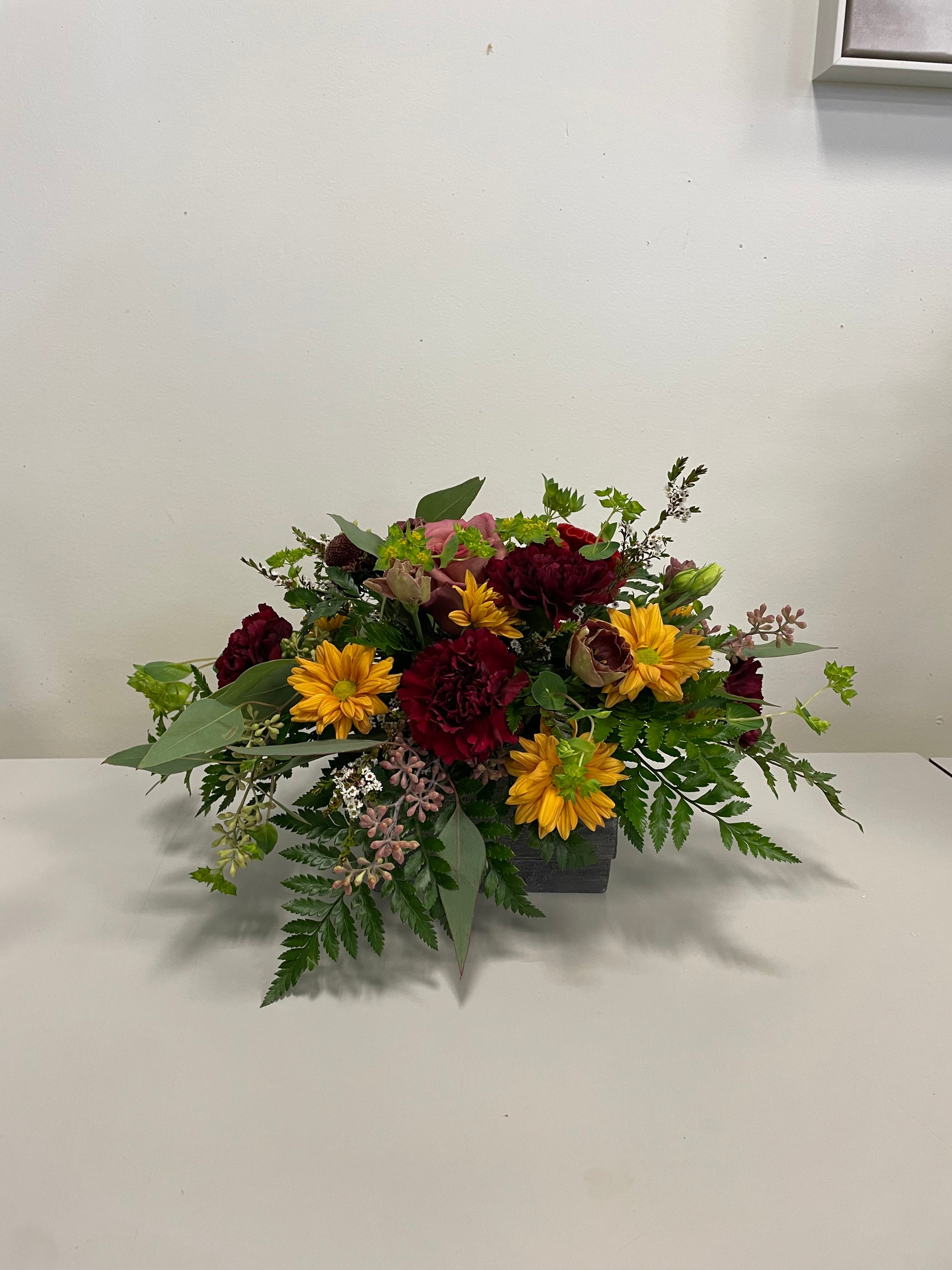 Join the Oct 6 Thanksgiving Small Centrepiece Workshop at 6 PM by Posies Flowers & Fashion Inc.—create a floral centrepiece with yellow daisies, red carnations, pink blooms and greenery in Bancroft, Ontario. Perfect for an autumn-themed class!.