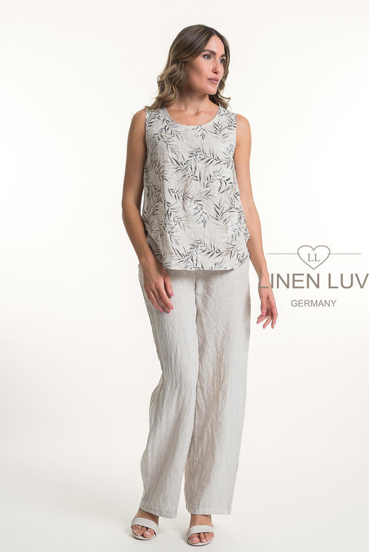 A woman wears the LinenLuv French Linen Top Print TP1131P-11 Beige with loose, light-colored linen pants and sandals. The background is plain white, featuring "LINEN LUV GERMANY" text on the right.