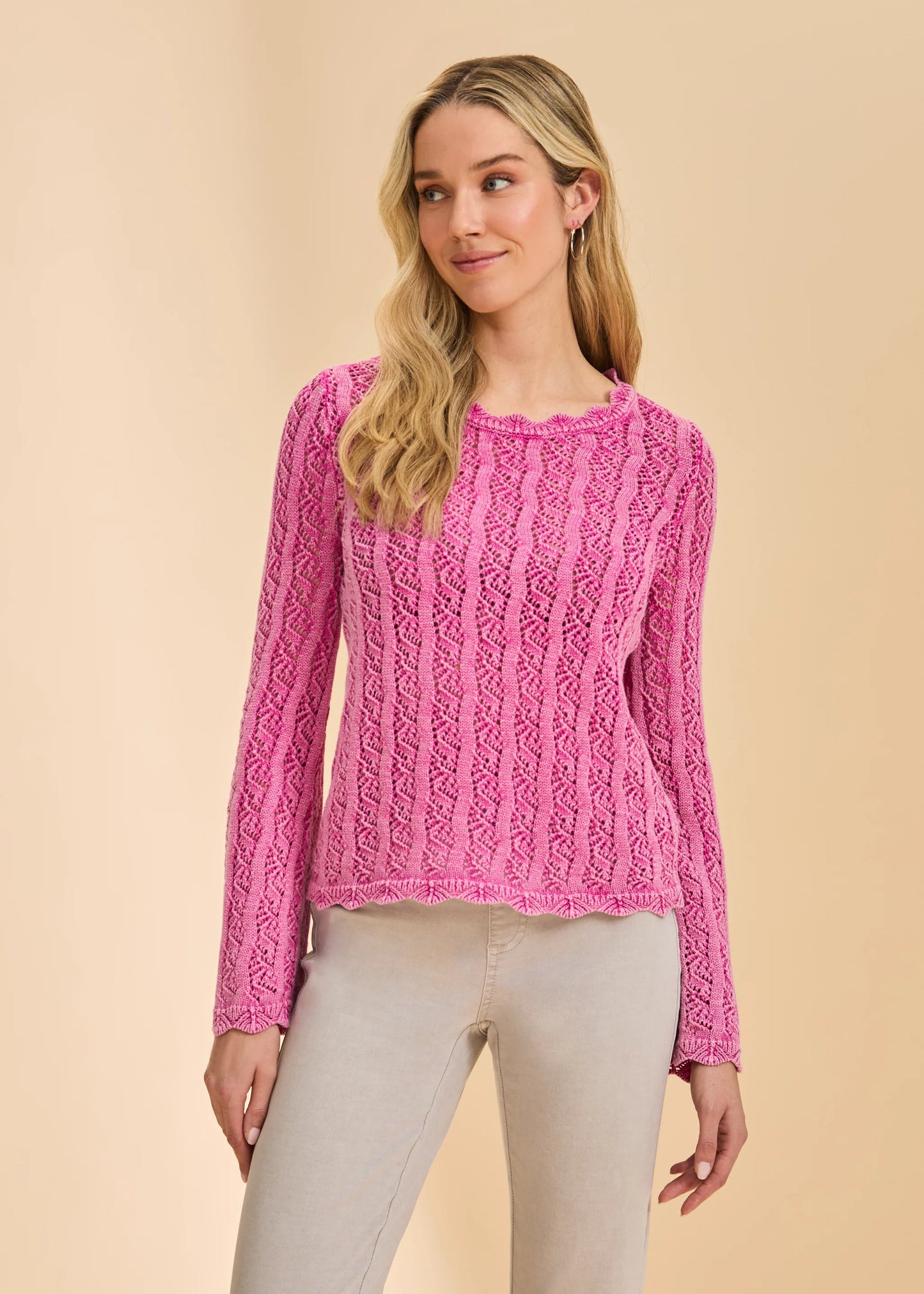 A woman stands against a beige background wearing the French Dressing Jeans Long Sleeve Garment Dye Sweater in Fuschia (1467314) with light beige pants, looking slightly left with a relaxed expression.