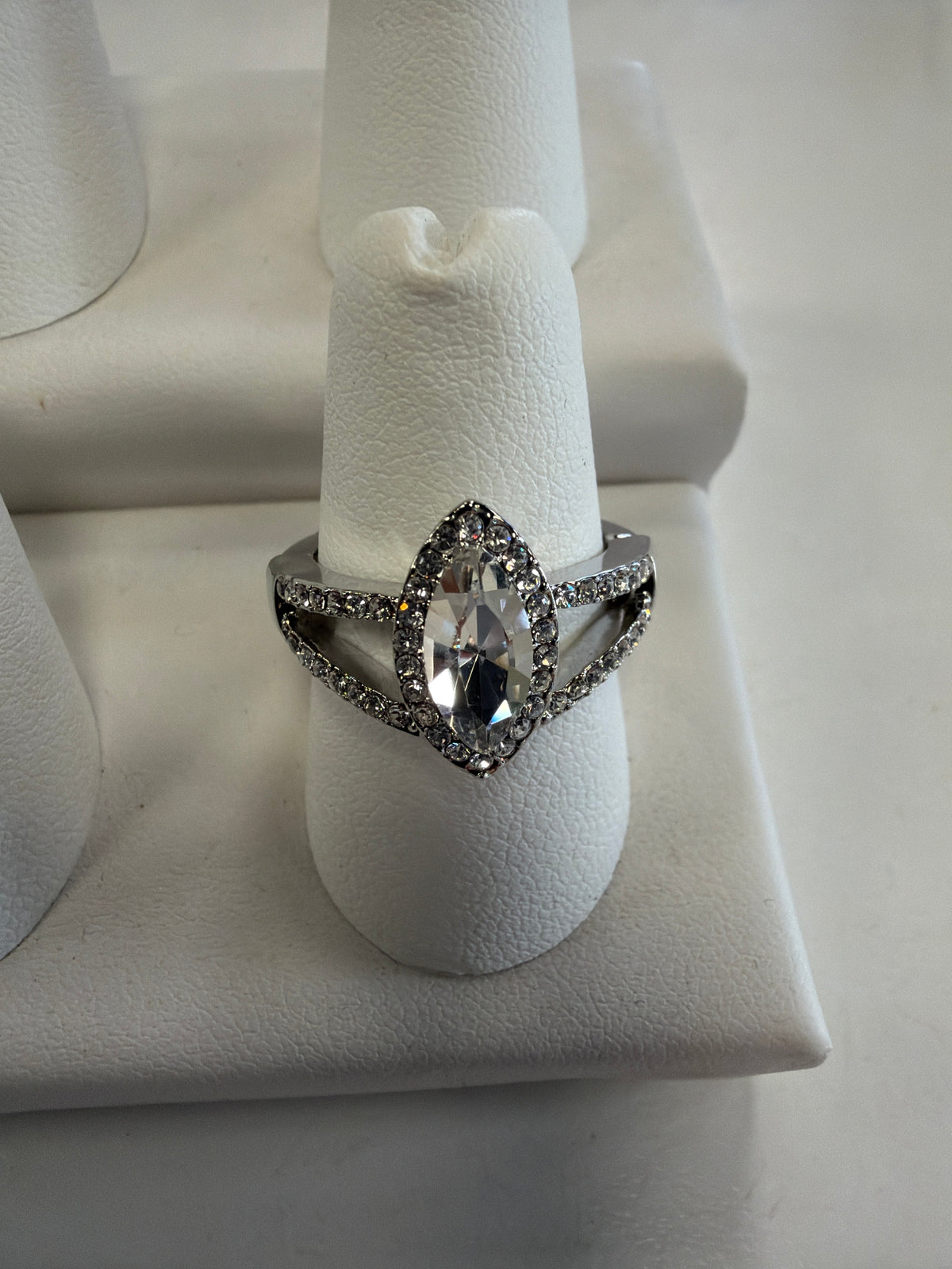 A silver-toned Jenna 69 ring featuring a large marquise CZ center stone surrounded by a halo of smaller stones and a split-shank band accented with pavé stones.