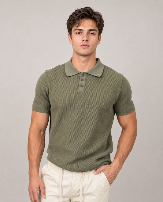 A young man with short brown hair wears the HEDGE Knit Polo Light Olive 56MS372S and light beige pants, standing against a plain light gray background with one hand in his pocket, looking at the camera.