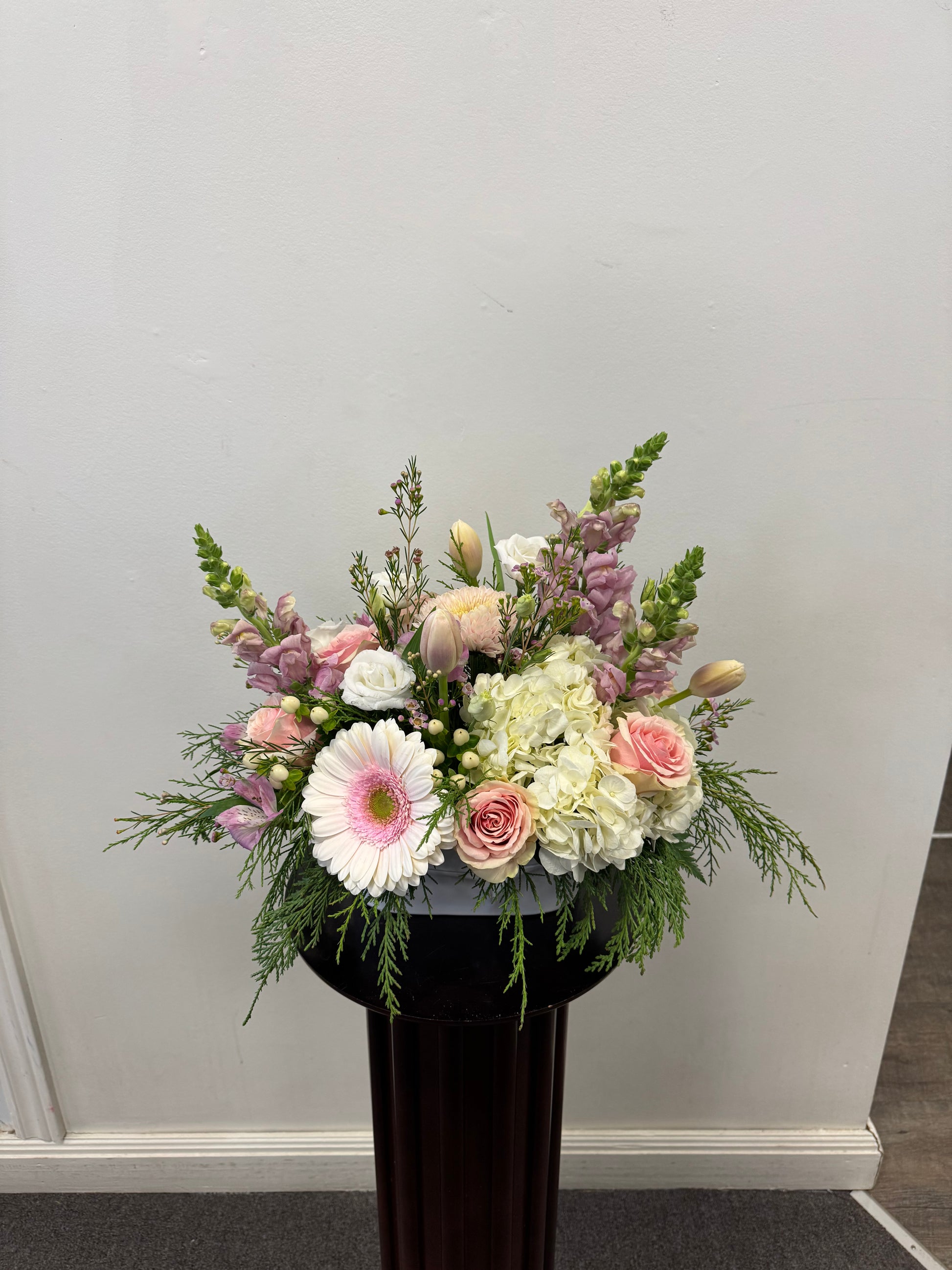 The Soft Elegance Arrangement by Posies Flowers & Fashion features pink gerberas, roses, white hydrangeas, tulips, and greenery in a black vase. Flower availability may vary and substitutions may affect image accuracy.