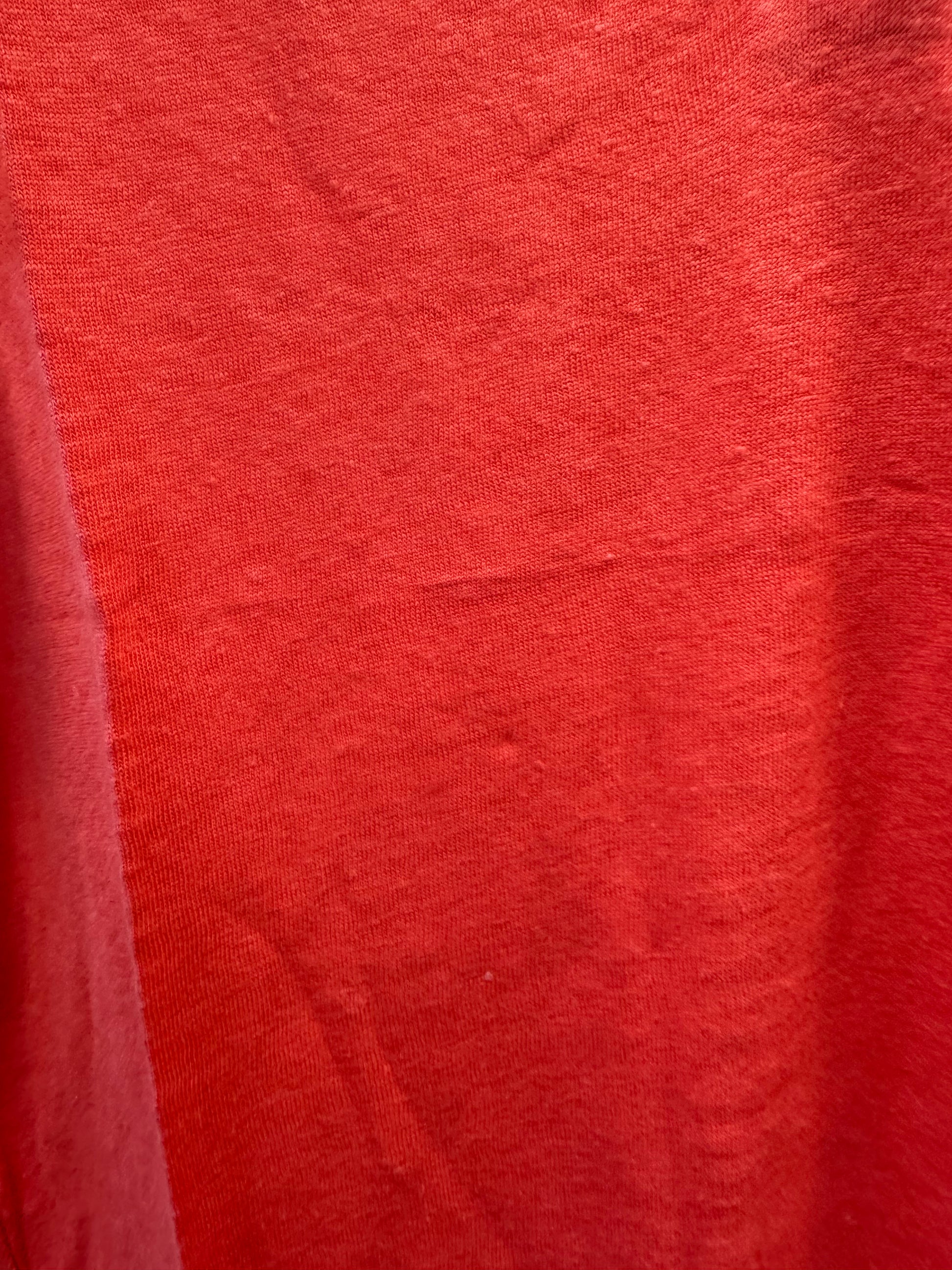 Close-up of the Feature Top CFO7825 by FOIL, showcasing red fabric with visible weave texture and subtle wrinkles. Slight shade variations add depth—perfect for a lightweight summer look.