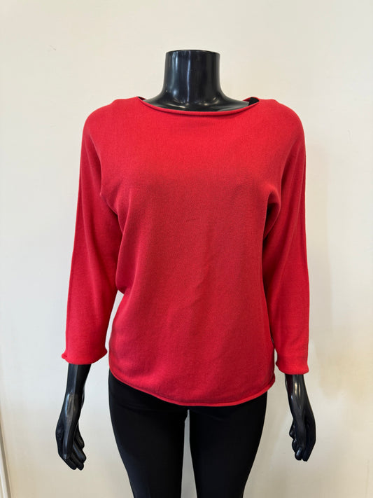 A black mannequin dressed in the ORIENTIQUE Knit Top Long Sleeve - Orientique, a red knit top made from organic cotton, paired with black pants is displayed against a plain white background. The top features a relaxed fit and a slightly rounded hem, with the mannequin's head and hands not shown.