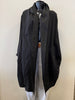 The mannequin showcases the Jacket Coverup WT111016-Pablo Tricot from Paolo Tricot, a loose-fitting long black coat with draped lapels over a black top, paired with light gray trousers against a simple light-colored background.