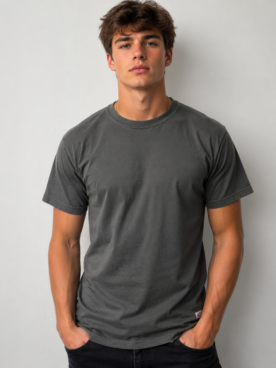 A young man with short brown hair stands against a plain light background, wearing a dark gray Northbound Supply Co T-shirt and black pants, hands in his pockets and a neutral expression on his face.