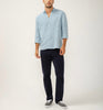 A man poses against a plain backdrop, wearing a light blue button-up and Machray Athletic Fit Straight Leg Pants Navy by Silver Jeans Co. His slightly wrinkled shirt enhances the relaxed stance, while gray sneakers finish his effortlessly stylish outfit.