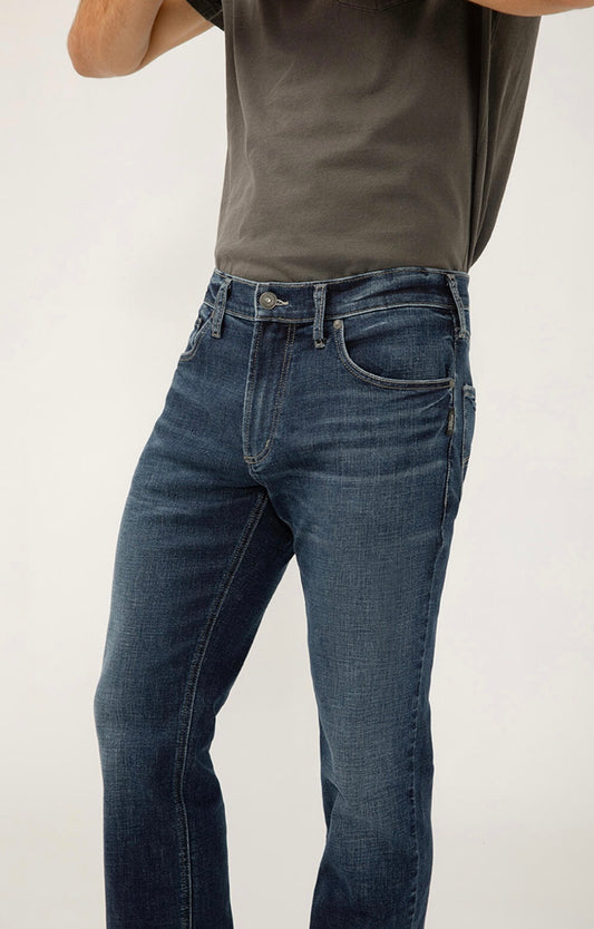 A person models the Silver Jeans Co. Konrad Slim Fit Slim Leg - M12225EFS303 jeans and a dark gray t-shirt, standing against a plain light background with their head and lower legs out of frame.