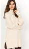 A woman with long brown hair is wearing a cream-colored JUMPER SWEATER from SoyaConcept. She is standing against a plain white background, with one arm relaxed by her side and the other slightly raised, touching her hair.