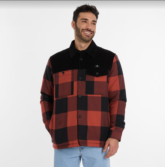 A man with short dark hair and a beard is wearing a CHECON Men's Jacket by RAGWEAR in red and black plaid, featuring a black collar and pocket flaps. He pairs it with light blue jeans and smiles against a plain white background.