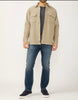 A man, with his head out of frame, is wearing a Silver Jeans Co. Button Up Knit Flex Shirt MJ0035KTS668 SILVER over a dark gray tee, paired with blue knit flex denim jeans and black sneakers against a plain background.
