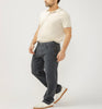 A man in a light beige polo, Silver Jeans Co. Grayson Classic Fit Straight Leg Knit Flex Jeans (M23425KTS668), and white sneakers stands against a plain light background, facing slightly sideways with one leg forward and arms relaxed.