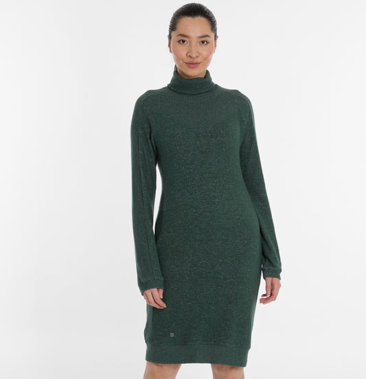 A woman stands against a plain white background wearing a long-sleeved, pine green PEONA Dress by RAGWEAR, looking confidently at the camera.