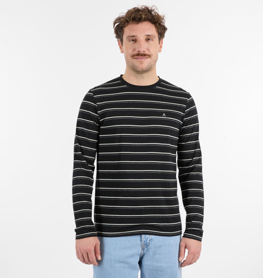 A man with short brown hair and a mustache stands against a plain white background, wearing the RAGWEAR ADDER STRIPE GOTS Long Sleeve men's shirt with thin white horizontal stripes and light blue jeans.