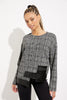 A woman with braided hair wears the black and multi-colored Checkered Faux Leather Top Style 233252 by Joseph Ribkoff, paired with black pants as she stands against a white background. She is slightly angled to one side, with a relaxed expression.