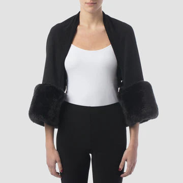 A person is modeling the Cover Up Style 153483X - BLACK by Joseph Ribkoff, featuring an open front that reveals a fitted white top underneath and black pants. The black wrap's faux-fur cuffs stand out, adding a luxurious touch against a plain, light gray background.