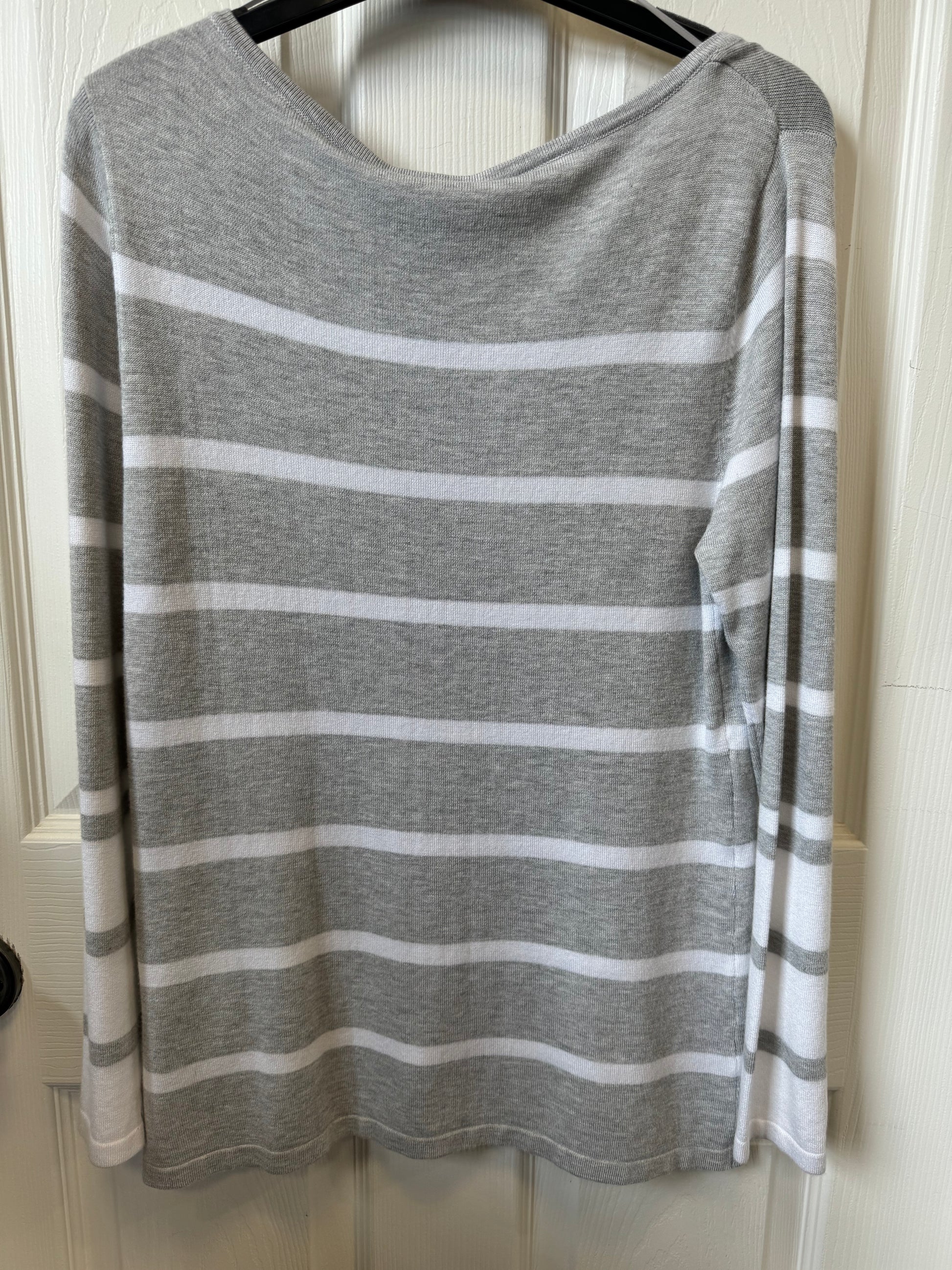 A MARBLE Grey/White Striped Fine Knit Sweater is displayed on a black coat hanger, hanging on a white door. This designer sweater features a round neckline and long sleeves.